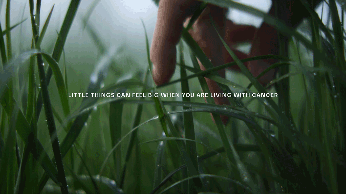 Hand touching grass with text "Little Things Can Feel Big When You Are Living with Cancer" 