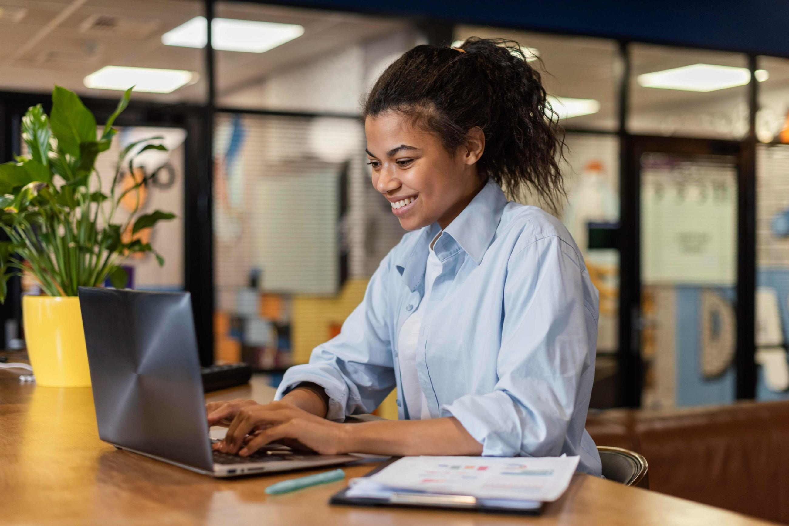 side-view-of-smiley-woman-working-with-laptop-in-the-office (1)