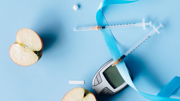 Two halfs of an apple, medical equipment, and a tablet on a blue background