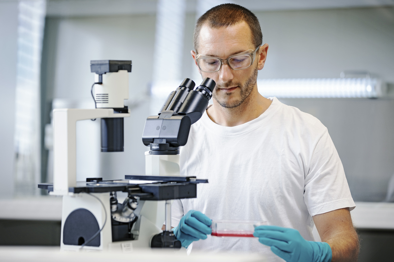 Empleado de laboratorio trabajando en un microscopio.