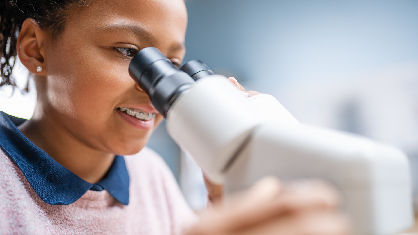 girl looking into microscope